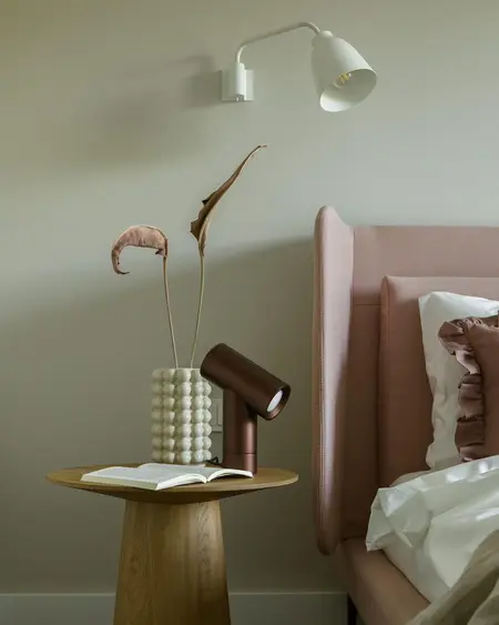 Sypialnia w stylu nowoczesnym z różowym łóżkiem, minimalistycznymi dodatkami i lampą.