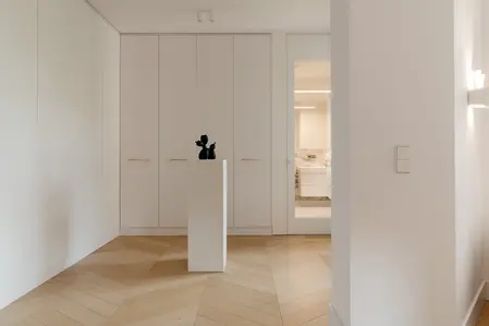 Garderoba w stylu minimalistycznym z białymi meblami i akcentami w kolorze drewna.