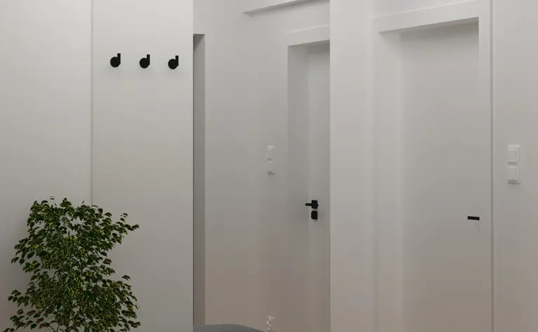 Minimalistyczny przedpokój z szarym siedziskiem i białymi ścianami, z rośliną.