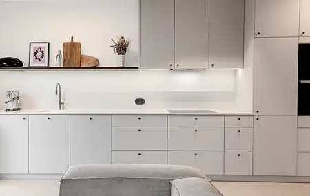 Wnętrze kuchni z szarymi meblami, białym blatem i akcentami boho, art deco i eklektycznymi.