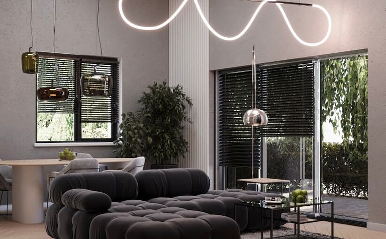 Przestronny salon z czarną, pikowaną sofą, oryginalnym oświetleniem LED w formie fali i dużymi oknami. Elegancki stolik kawowy i rośliny dodają wnętrzu stylu i świeżości.