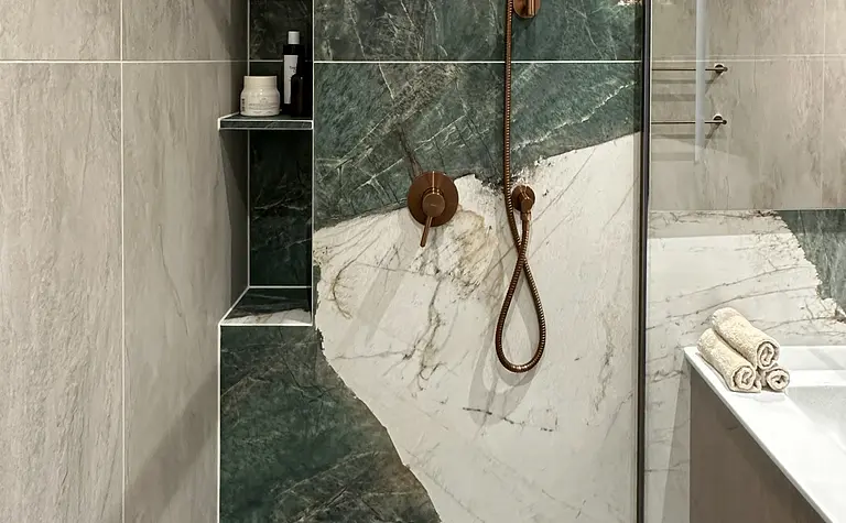 Nowoczesna łazienka z zielonymi płytkami i złotymi detalami.