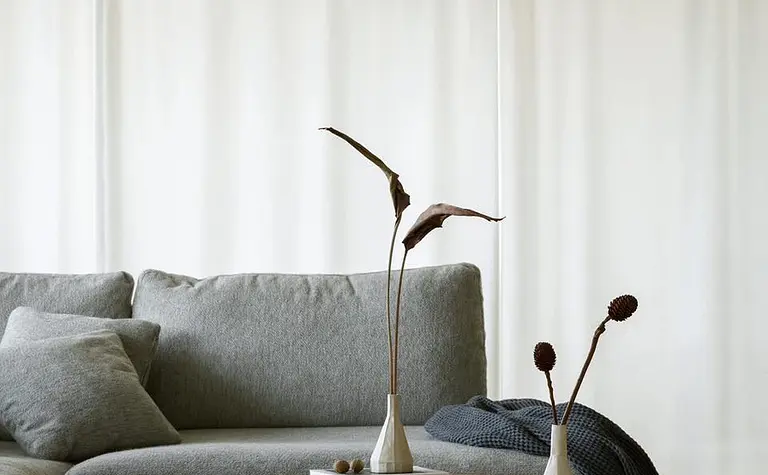 Wnętrze salonu z szarym narożnikiem i minimalistycznymi dekoracjami w stylu quiet luxury.