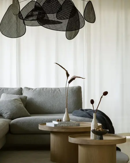 Wnętrze salonu z szarym narożnikiem i minimalistycznymi dekoracjami w stylu quiet luxury.