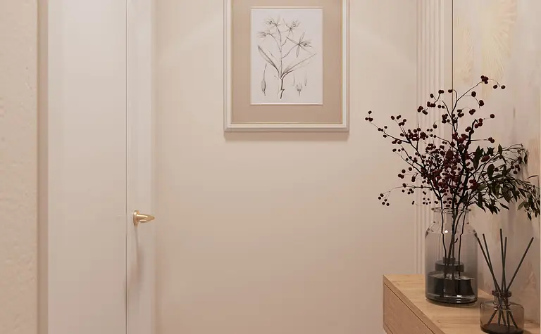 Minimalistyczny korytarz z drewnianą komodą i roślinami w nowoczesnym stylu.