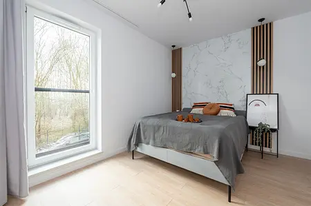 Wnętrze sypialni z szarym łóżkiem, marmurową ścianą, styl minimaluxe, nowoczesny i soft minimalizm.