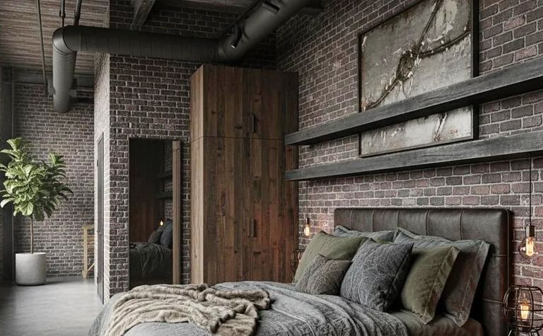 Sypialnia w stylu industrialnym z drewnianym łóżkiem i ceglaną ścianą.