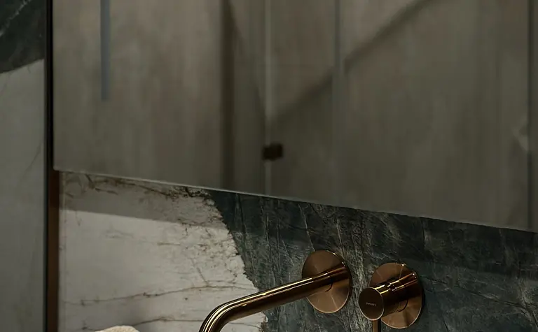 Wnętrze łazienki z umywalką, marmurowymi płytkami, złotym kranem i ręcznikami.