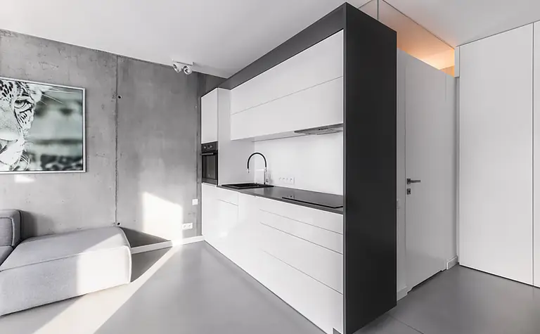 Wnętrze kuchni w stylu industrialnym i minimalistycznym z białymi meblami.