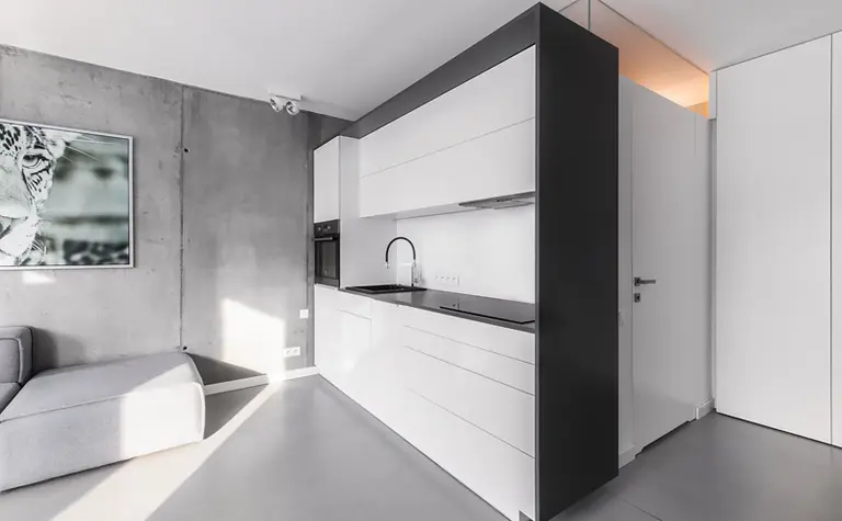 Wnętrze kuchni w stylu industrialnym i minimalistycznym z białymi meblami.