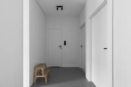 Przedpokój z minimalistycznym wystrojem, białe ściany i drewniana ławka.