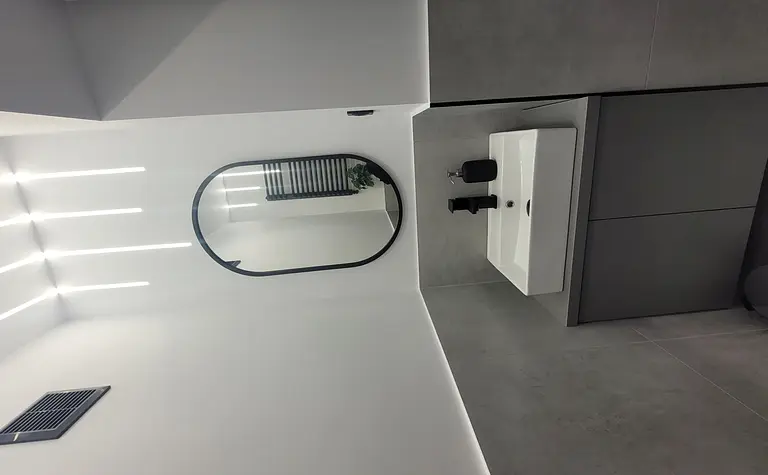 Nowoczesna łazienka z białą umywalką i szarymi płytkami w stylu minimalistycznym.