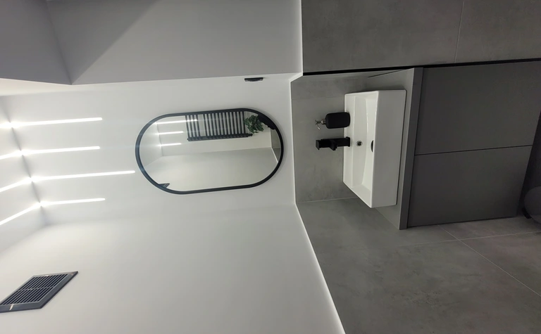 Nowoczesna łazienka z białą umywalką i szarymi płytkami w stylu minimalistycznym.