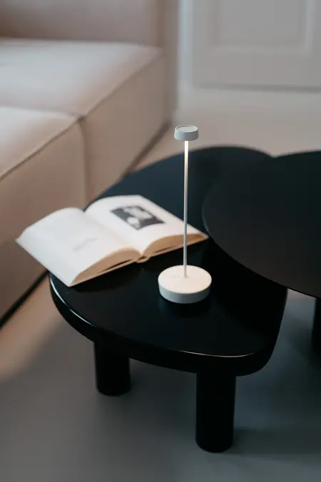 Eklektyczne wnętrze z minimalistycznym stolikiem, lampą i książką.