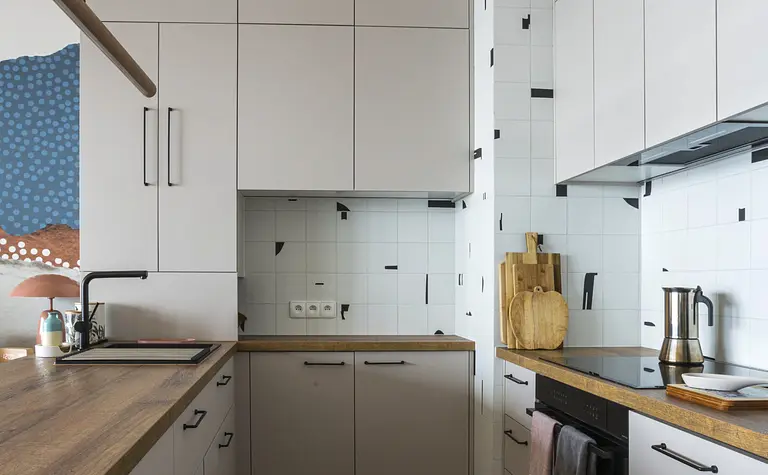 Kuchnia w stylu boho i współczesnym z białymi meblami i drewnianymi akcentami.