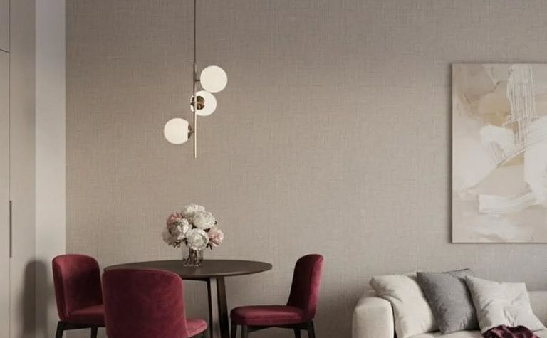 Wnętrze jadalni z okrągłym stołem, bordowymi krzesłami i nowoczesnym oświetleniem w stylu minimaluxe.