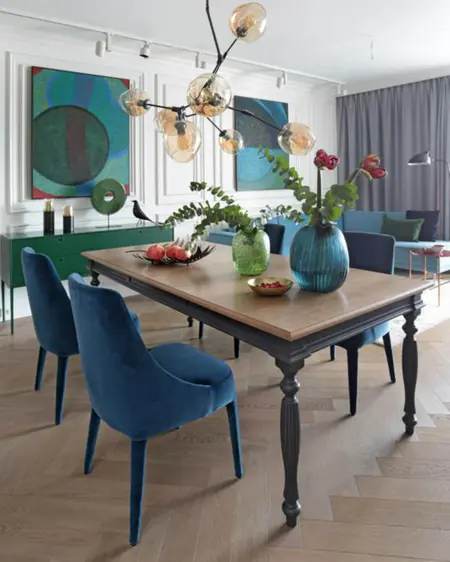 Wnętrze jadalni z niebieskimi krzesłami i dekoracjami w stylach minimaluxe oraz quiet luxury.