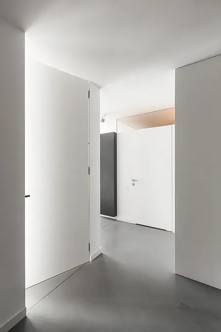 Wnętrze przedpokoju z białymi drzwiami i szarym podłogą w stylu industrialnym, minimalistycznym, nowoczesnym.