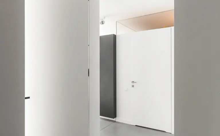 Wnętrze przedpokoju z białymi drzwiami i szarym podłogą w stylu industrialnym, minimalistycznym, nowoczesnym.