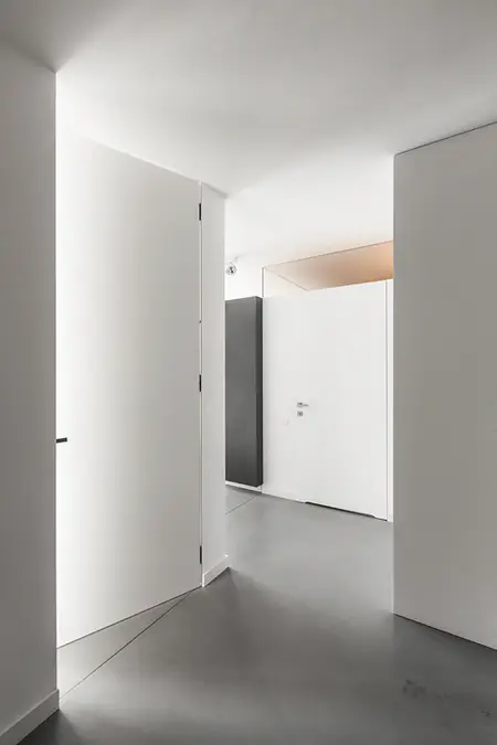 Wnętrze przedpokoju z białymi drzwiami i szarym podłogą w stylu industrialnym, minimalistycznym, nowoczesnym.