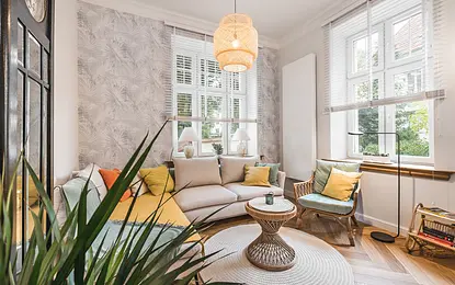 Wnętrze eklektycznego salonu z jasnym narożnikiem i kolorowymi akcentami.