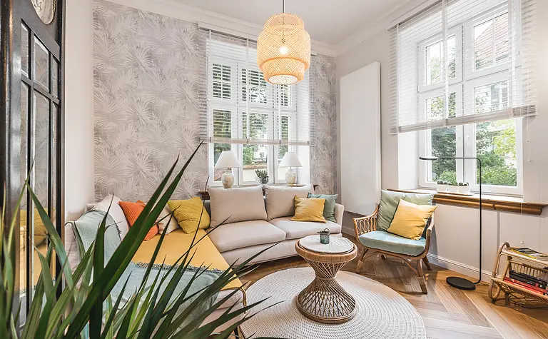 Wnętrze eklektycznego salonu z jasnym narożnikiem i kolorowymi akcentami.