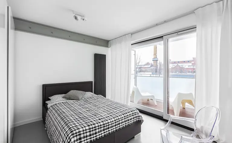 Sypialnia w stylu industrialnym i minimalistycznym z dużymi oknami i nowoczesnym łóżkiem.