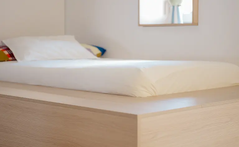 Sypialnia w stylu eklektycznym z minimalistycznym łóżkiem oraz dużym lustrem