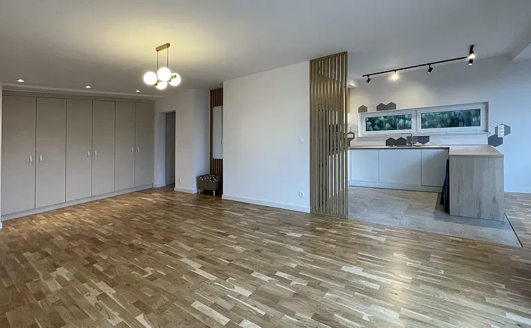 Eklektyczne wnętrze mieszkania z kuchnią, szafami i drewnianą podłogą.