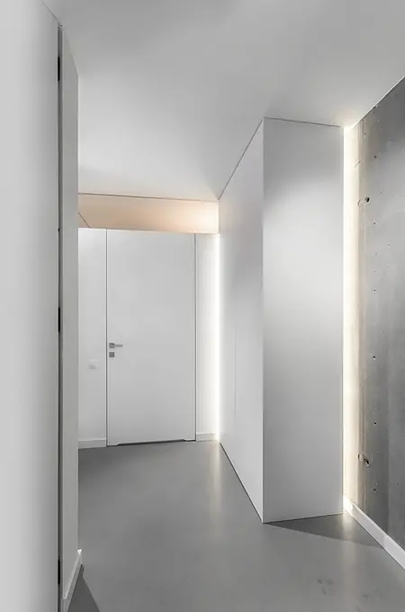 Wnętrze przedpokoju w stylu industrialnym i minimalistycznym z białymi ścianami i szarym podłogą.