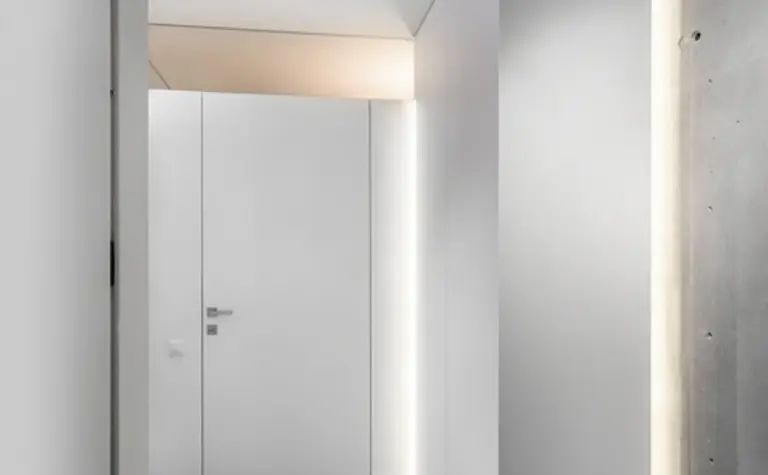 Wnętrze przedpokoju w stylu industrialnym i minimalistycznym z białymi ścianami i szarym podłogą.