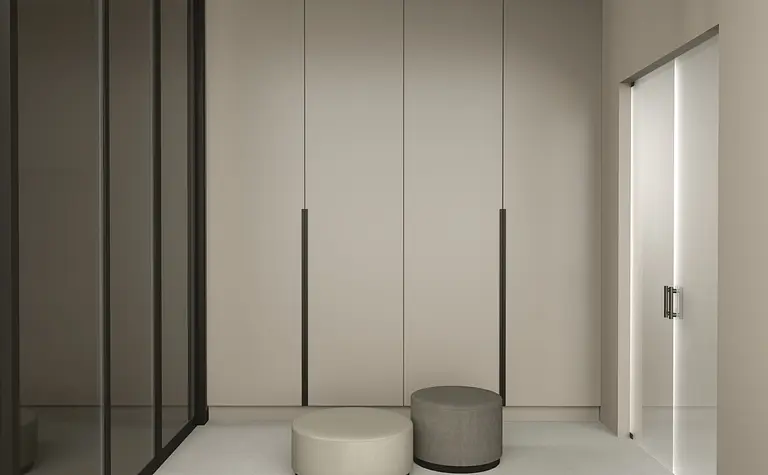 Nowoczesny przedpokój z szafą, szarym i beżowym siedziskiem, w stylu quiet luxury.