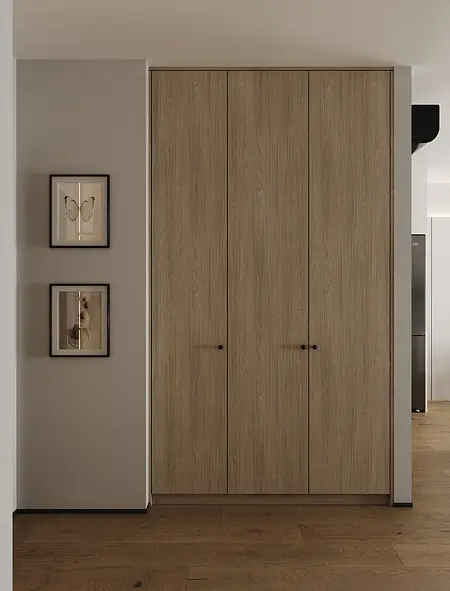 Wnętrze garderoby z drewnianymi szafami, minimalistycznymi obrazami i industrialnym stylem.