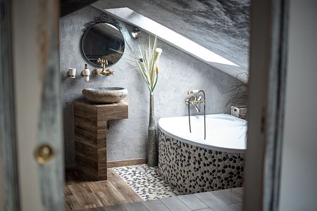Wnętrze łazienki z industrialnym i rustykalnym stylem, okrągła wanna, drewniana umywalka.