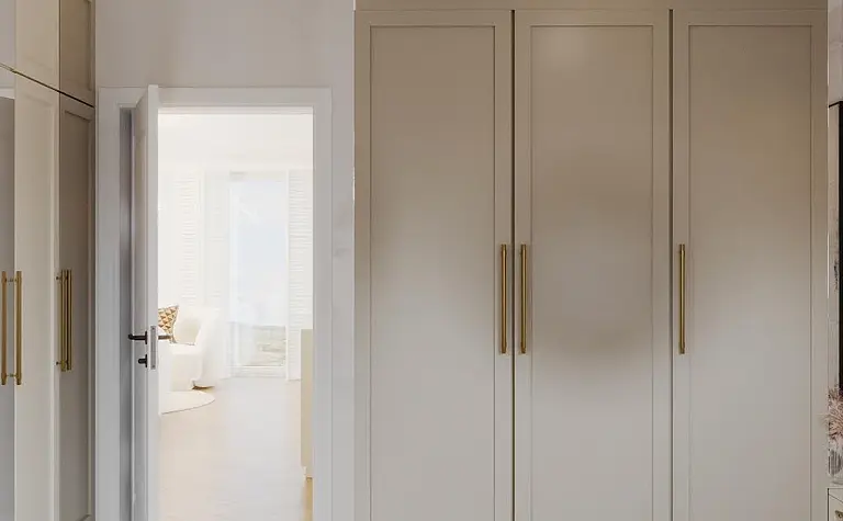 Garderoba w stylu art deco i eklektycznym, z beżowymi szafami i dużym lustrem.