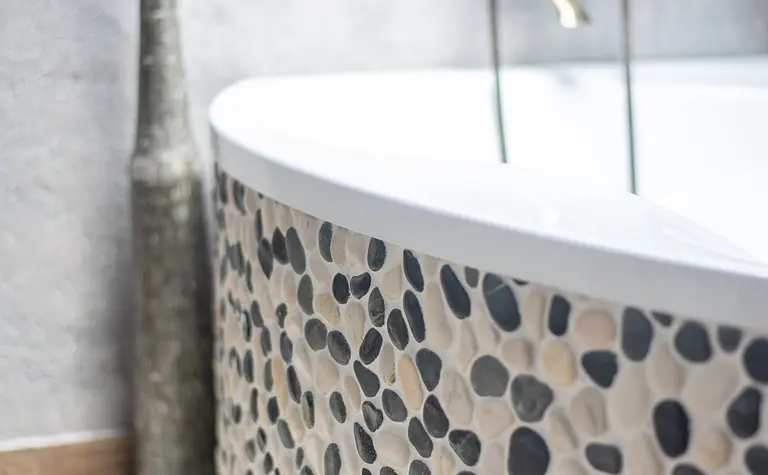 Wnętrze łazienki z okrągłą wanną i kamiennymi detalami w stylu rustykalnym i industrialnym.