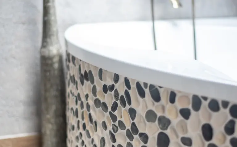 Wnętrze łazienki z okrągłą wanną i kamiennymi detalami w stylu rustykalnym i industrialnym.
