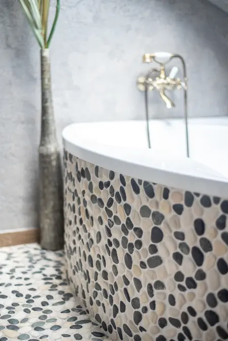 Wnętrze łazienki z okrągłą wanną i kamiennymi detalami w stylu rustykalnym i industrialnym.