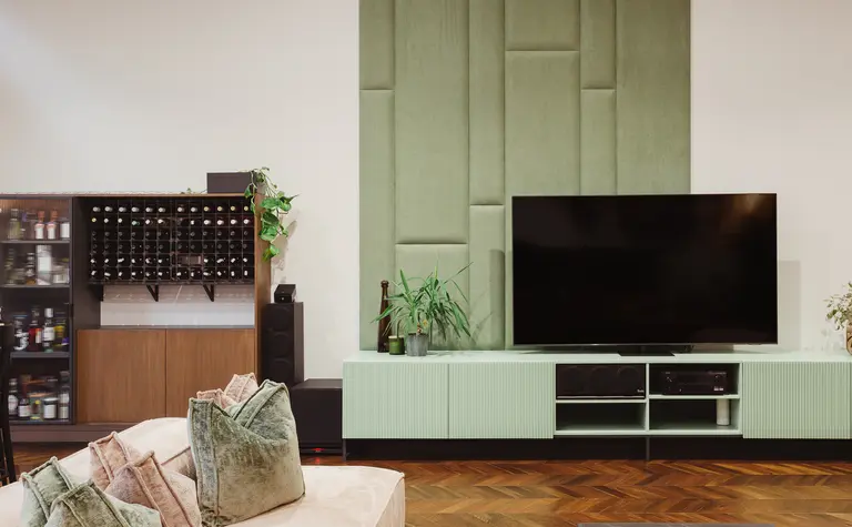 Wnętrze salonu w stylu dopamine decor, eklektycznym i rustykalnym z zieloną ścianą.