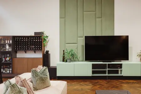 Wnętrze salonu w stylu dopamine decor, eklektycznym i rustykalnym z zieloną ścianą.