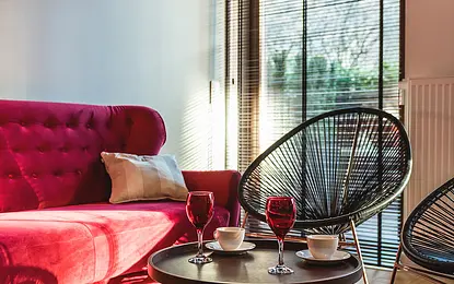 Wnętrze salonu z różową sofą, czarnymi fotelami i stołem kawowym w stylu eklektycznym.