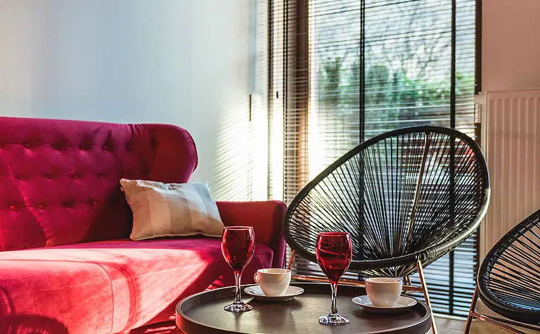 Wnętrze salonu z różową sofą, czarnymi fotelami i stołem kawowym w stylu eklektycznym.