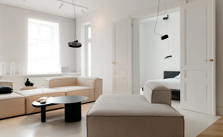 Wnętrze salonu w stylu eklektycznym i minimalistycznym z beżowymi meblami i czarnymi detalami.
