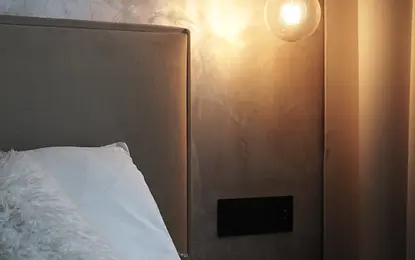 Sypialnia w stylu boho i minimalistycznym z szarymi ścianami i oświetleniem.