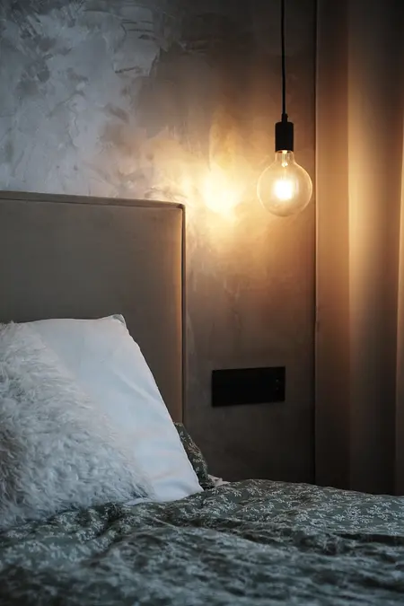 Sypialnia w stylu boho i minimalistycznym z szarymi ścianami i oświetleniem.