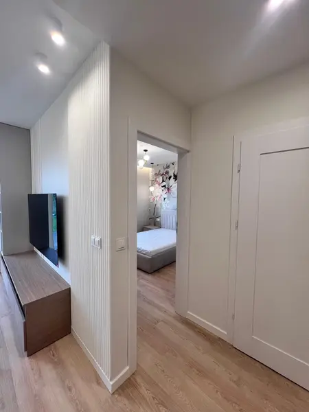 Przedpokój z jasnymi ścianami, drewnianą podłogą oraz nowoczesnymi akcentami.