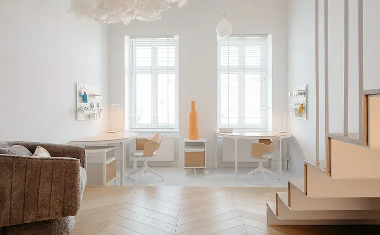 Eklektyczne biuro z minimalistycznym wystrojem, jasnymi meblami i drewnianą podłogą.