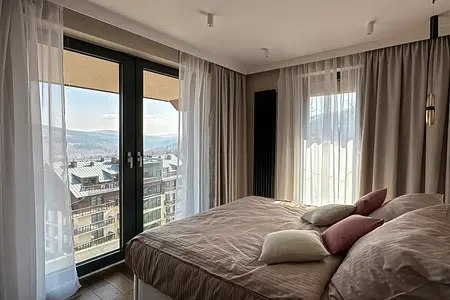 Sypialnia z dużym łóżkiem, poduszkami i zasłonami, nowoczesna aranżacja