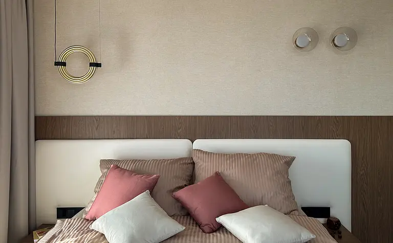 Wnętrze sypialni z brązowym łóżkiem, poduszkami i nowoczesnym oświetleniem.