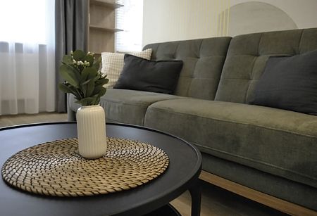 Wnętrze salonu w stylu minimalistycznym z zieloną sofą i czarnym stolikiem.